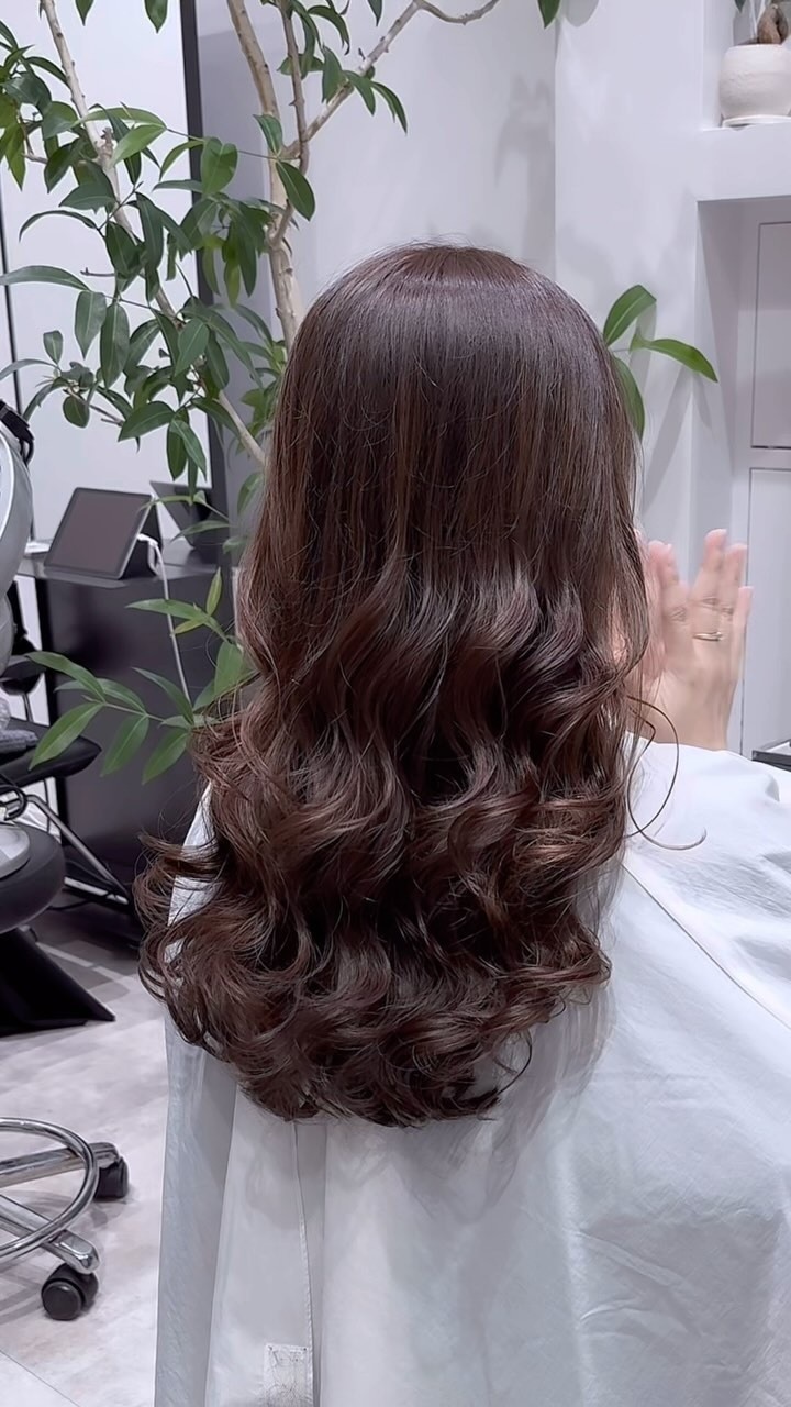 深みのあるブラウンのロングヘアにゆるい大きめカールをかけた後ろ姿