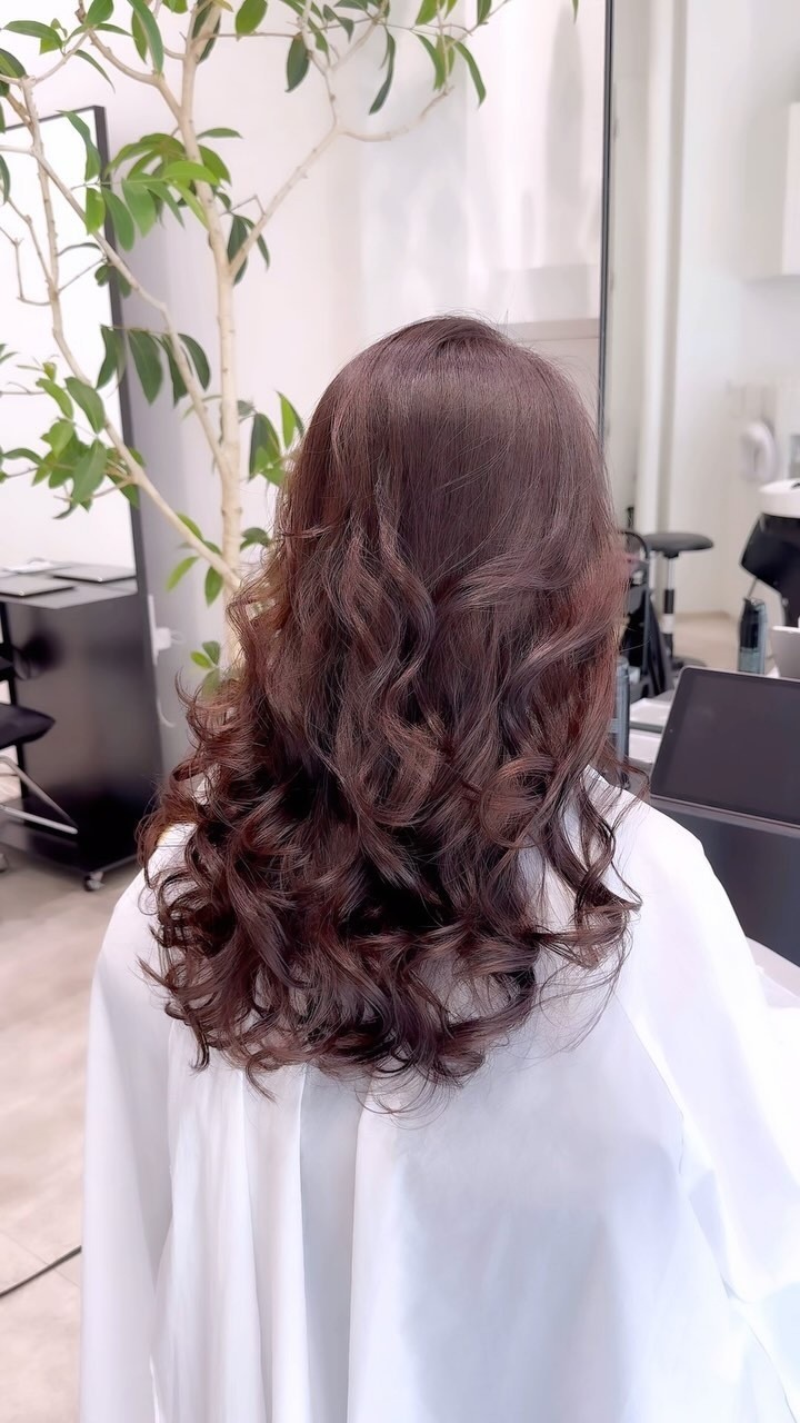 赤みブラウンのロングヘアに柔らかな縦カールを重ねた後ろ姿