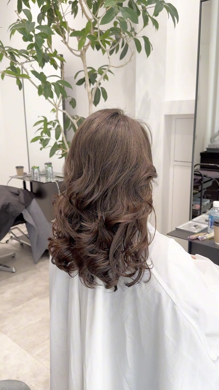 アッシュブラウンのロングヘアに毛先まで大きなカールをかけた後ろ姿