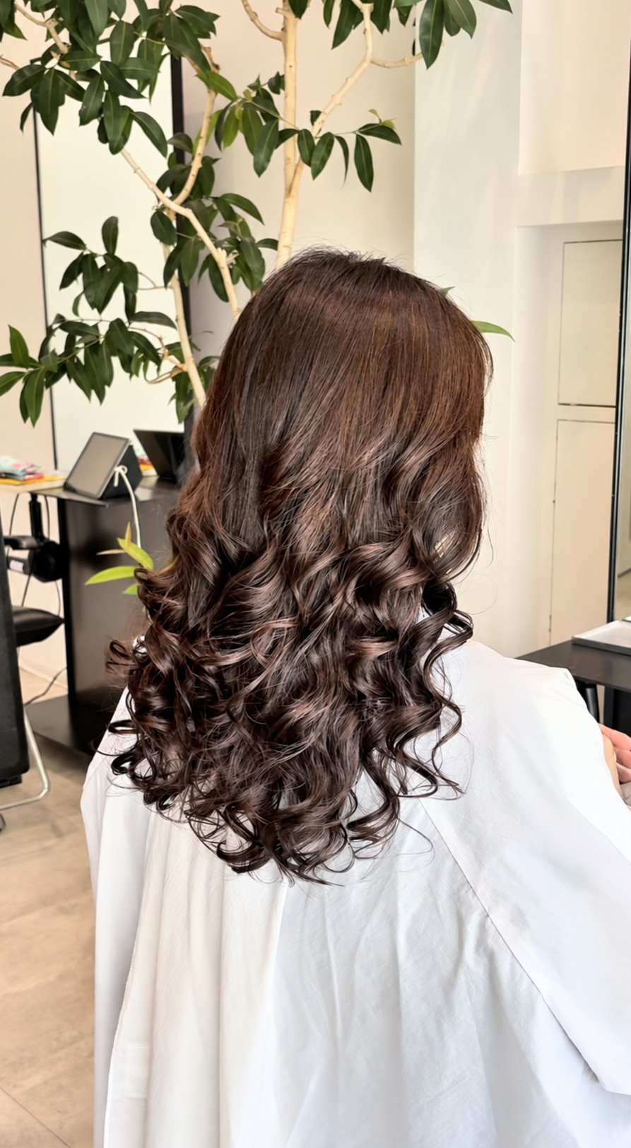 ダークブラウンのロングヘアにしっかりしたカールをかけた後ろ姿