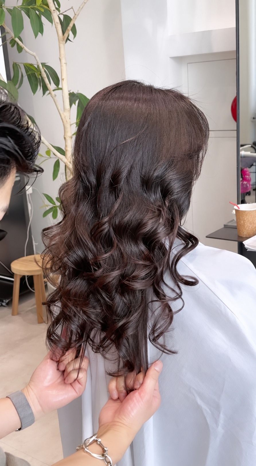ダークブラウンのロングヘアに大きな縦カールをかけた後ろ姿
